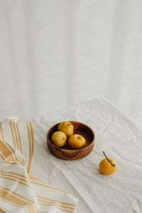 Kaboompics - Wooden Bowl of Japanese Quince with a Single Fruit Outside, Vertical Neutral Food Styling