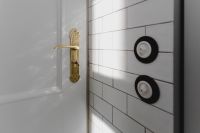 Kaboompics - Antique Brass Door Handle and Two Black Switches on White Subway Tile, Wide Interior View