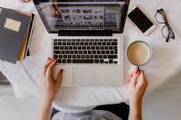 Kaboompics - Overhead Laptop Work Setup with Coffee, Phone and Glasses as a Woman Works from Bed