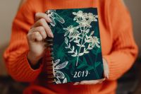Kaboompics - A woman in an orange sweater holds the 2019 calendar in her hands