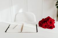 Kaboompics - Red Rose Bouquet Beside Open Planner on White Desk with Copy Space