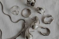Kaboompics - Silver Chain and Jewelry in Chrome Bowl on Speckled Gray Stone