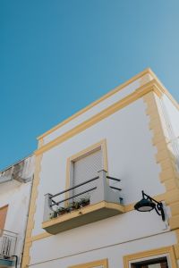 Kaboompics - Sunlit Rooftop Cornice and Shuttered Window Against Blue Sky
