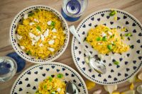 Kaboompics - Yellow rice with greens on a cute plate with blue hearts and a table decorated with flower petals