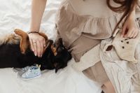 Kaboompics - Pregnant Woman with Small Dog Beside Baby Clothes