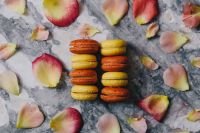 Kaboompics - Overhead Flat Lay of Yellow and Orange Macarons with Rose Petals on Marble
