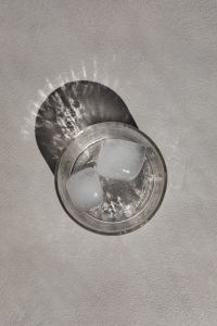 Kaboompics - Overhead Glass of Iced Water with Two Ice Cubes, Bold Circular Shadow and Minimal Drink Background