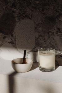 Kaboompics - White Candle and Ceramic Bowl with Wooden Scoop Against Marble Wall