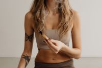 Kaboompics - Seated Woman Holding a Smoking Palo Santo Stick in a Wide Composition