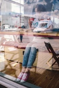 Kaboompics - Woman Reading a Book with Coffee Behind a Cafe Window