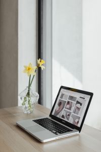 Kaboompics - Glass Vase with Yellow Daffodils beside an Open Laptop on a Bright Home Office Desk