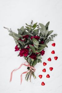Valentine's Day Flat Lay with Red Heart Pralines, Burgundy Flowers and White Marble