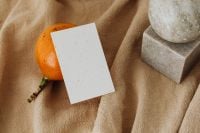 Kaboompics - Orange Fruit with Blank Business Card and Stone Decor on Beige Linen
