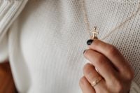 Kaboompics - Hand Holding a Gold Cross Pendant against a White Knit Sweater