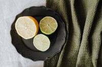 Kaboompics - Lemon and Lime Slices on Black Stoneware with Olive Green Linen, Minimal Citrus Background