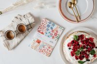 Kaboompics - Pavlova Dessert Flat Lay with Coffee, Floral Recipe Card and Gold Cutlery