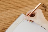 Kaboompics - Close-Up of Hand Using Gold Pen in Notebook