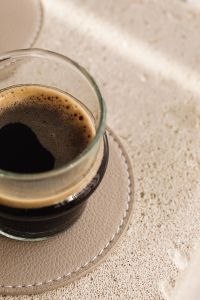 Kaboompics - Foamy Espresso in Clear Glass on a Textured Beige Surface