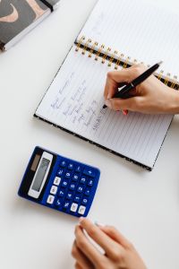 Kaboompics - Top View of Hand Writing in a Notebook Beside a Calculator