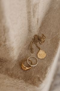 Kaboompics - Gold and Silver Rings with a Delicate Gold Chain on Soft Neutral Fabric, Jewelry Still Life