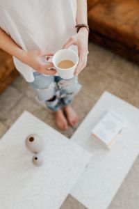 A woman with a cup of coffee reads a book
