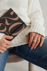 Kaboompics - Faceless Woman in White Sweater Holding Patterned Book and Wearing Rings