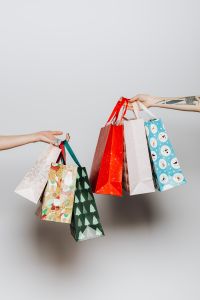 Kaboompics - Christmas Gift Bags Passed Between Two Hands, Tight Colorful Holiday Shopping Crop
