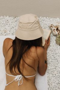 Kaboompics - Overhead View of Woman Reading in a Bucket Hat on White Pebbles