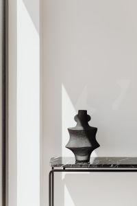 Kaboompics - Black Sculptural Vase On Marble Console With Sunlight