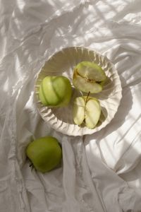 Kaboompics - Cut Green Apples in a Fluted White Bowl beside a Whole Apple, Sunlit Linen Still Life