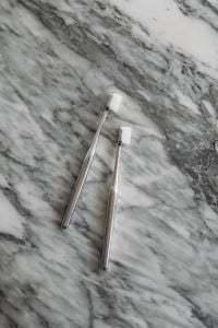 Kaboompics - Two White Toothbrushes Diagonally Arranged on Veined Marble, Bathroom Care Flat Lay