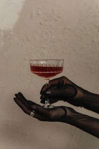 Kaboompics - Black Gloved Hands Holding a Red Cocktail Glass