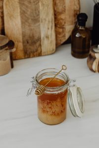 Kaboompics - Honey Jar with Wooden Dipper Styled on a Neutral Kitchen Counter