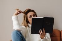 Kaboompics - Woman Holding a Black Bible in a White Sweater and Jeans