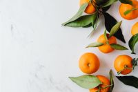 Kaboompics - Ripe Mandarin Oranges and Leaves on White Marble with Copy Space for Fresh Food Branding
