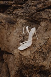 Kaboompics - White Strappy High Heels Among Shoreline Rocks