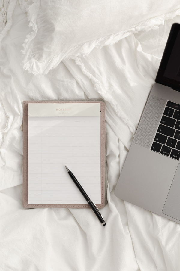 Working with a laptop in bed - white cotton bedding - blank notebook ...