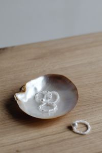 Kaboompics - Pearl Bead Rings in a Seashell on a Wood Table with Copy Space
