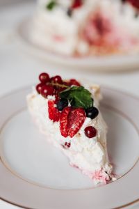 Kaboompics - Pavlova Slice with Raspberries, Red Currants and Mint on a White Plate