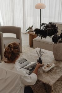 Kaboompics - Woman Reading Beside Books and a Reed Diffuser on a Marble Table