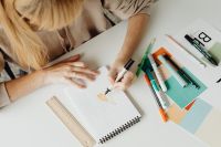 Kaboompics - Designer Drawing a Colorful Design in a Sketchbook with Markers, Overhead Work Scene