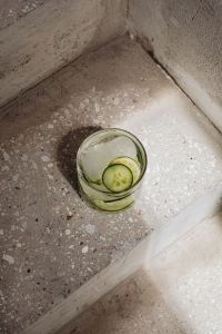 Kaboompics - Cucumber and Lime Water with Ice on a Terrazzo Stair, Sunlit Concrete Corner and White Linen
