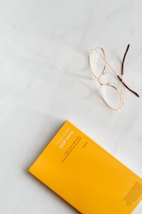 Books And Eyeglasses On White Marble: Minimalist Flat Lay