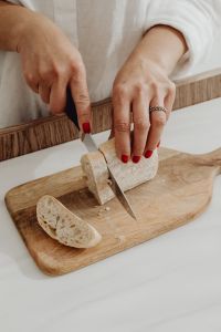 Kaboompics - Overhead View of Hands Slicing Rustic Bread