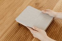 Kaboompics - Hand Holding a Neutral Notebook on Wooden Desk