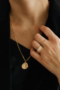 Kaboompics - Woman Touching Gold Pendant Necklace with Ringed Fingers