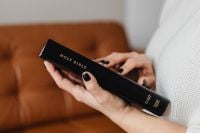 Kaboompics - Hands Holding a Closed Holy Bible on a Brown Leather Sofa