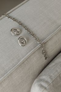 Kaboompics - Silver Chain and Spiral Earrings on a Neutral Sofa