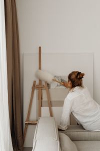 Kaboompics - Woman Dusting a Framed Artwork at Home