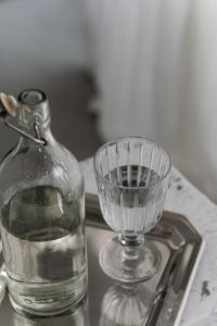Kaboompics - Glass Bottle and Ribbed Glass on Reflective Silver Tray